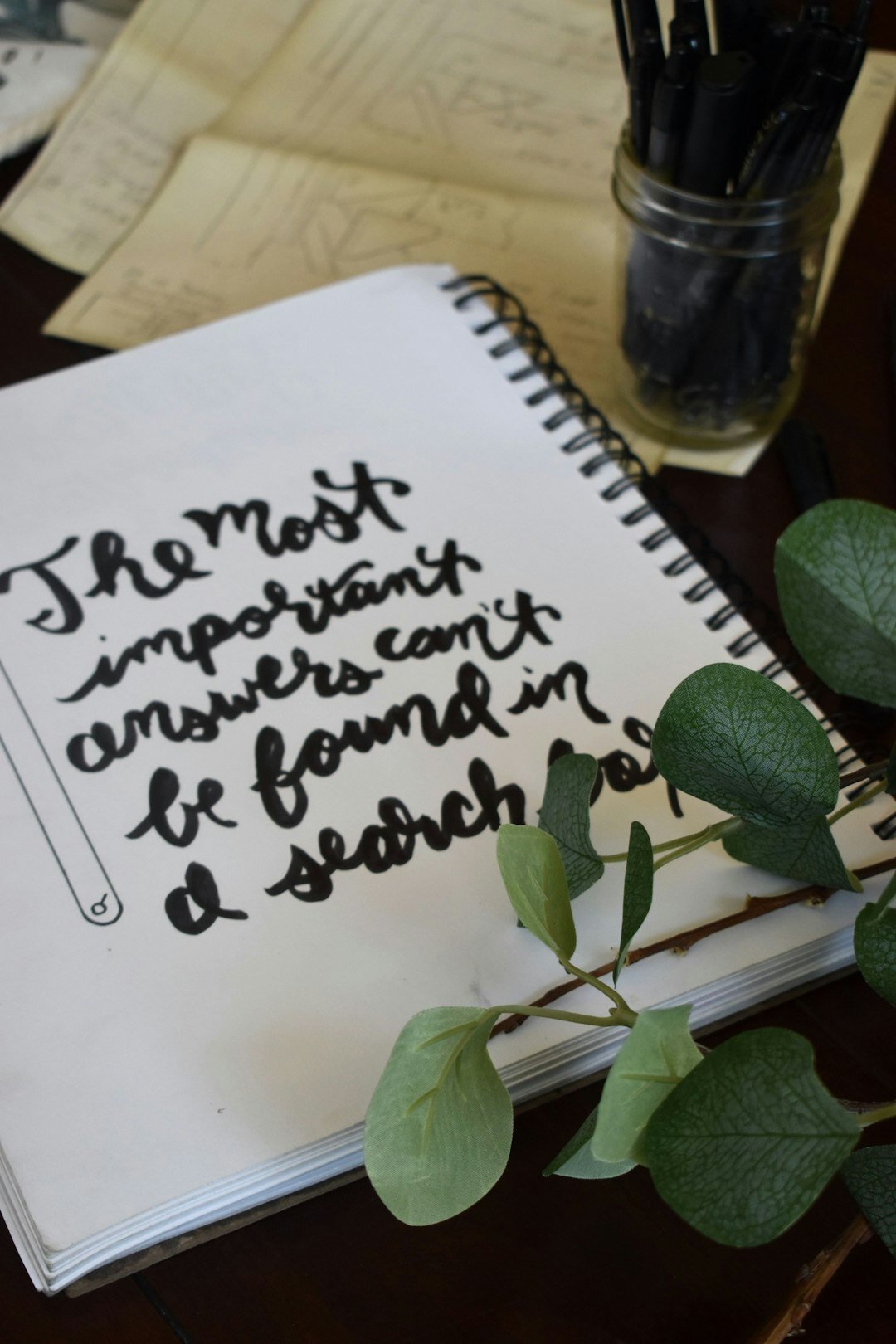 Open notebook with handwritten notes, a pen and a magnifying glass